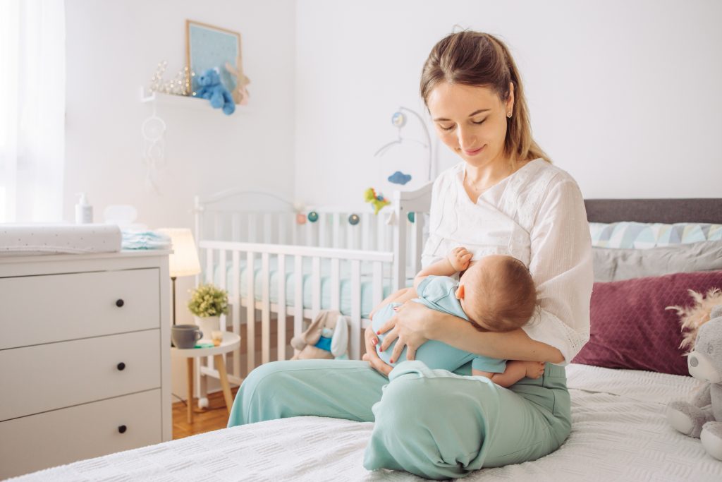 mother sitting on a bed breastfeeding