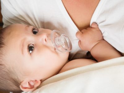 baby with pacifier in mother arm