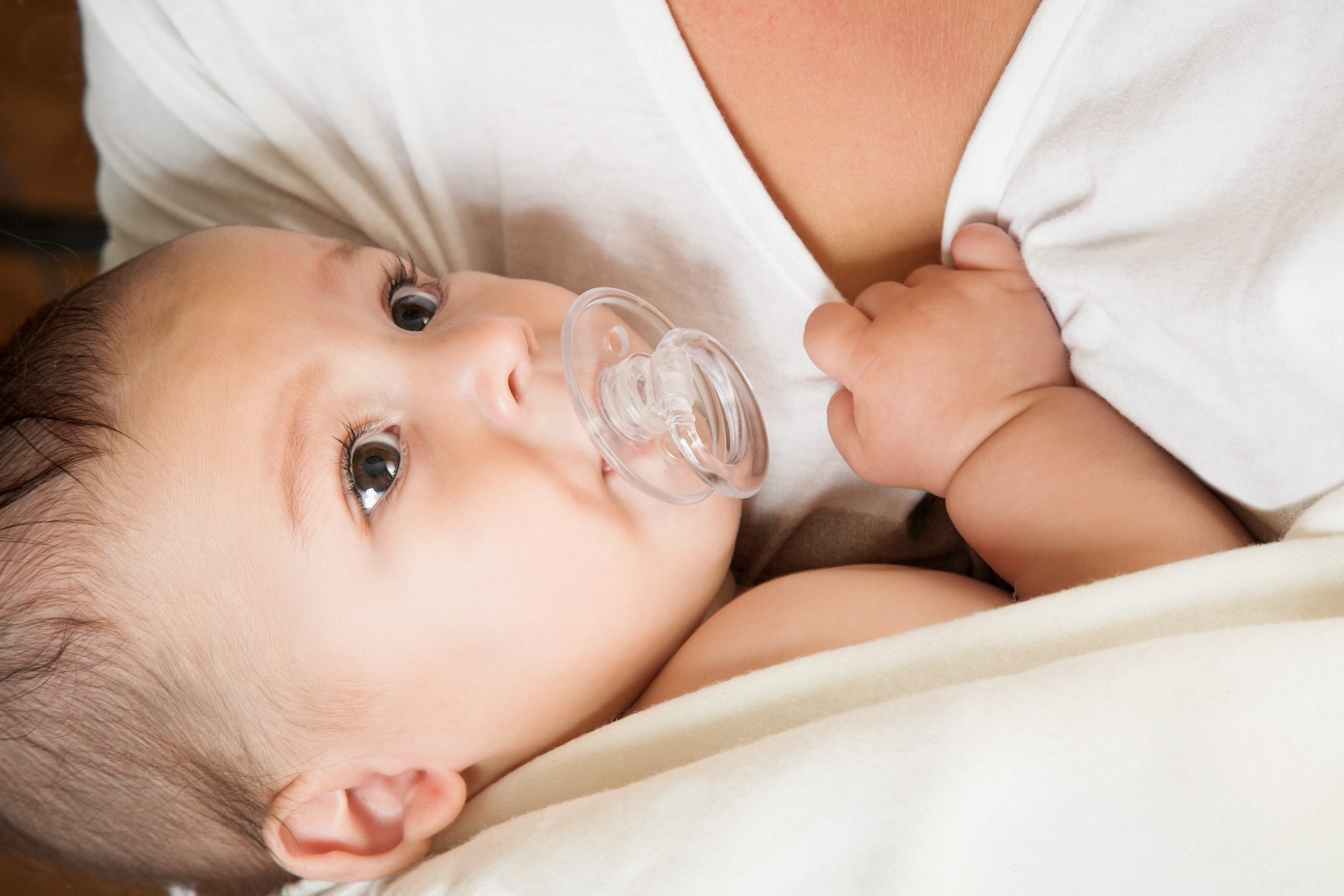 baby with pacifier in mother arm