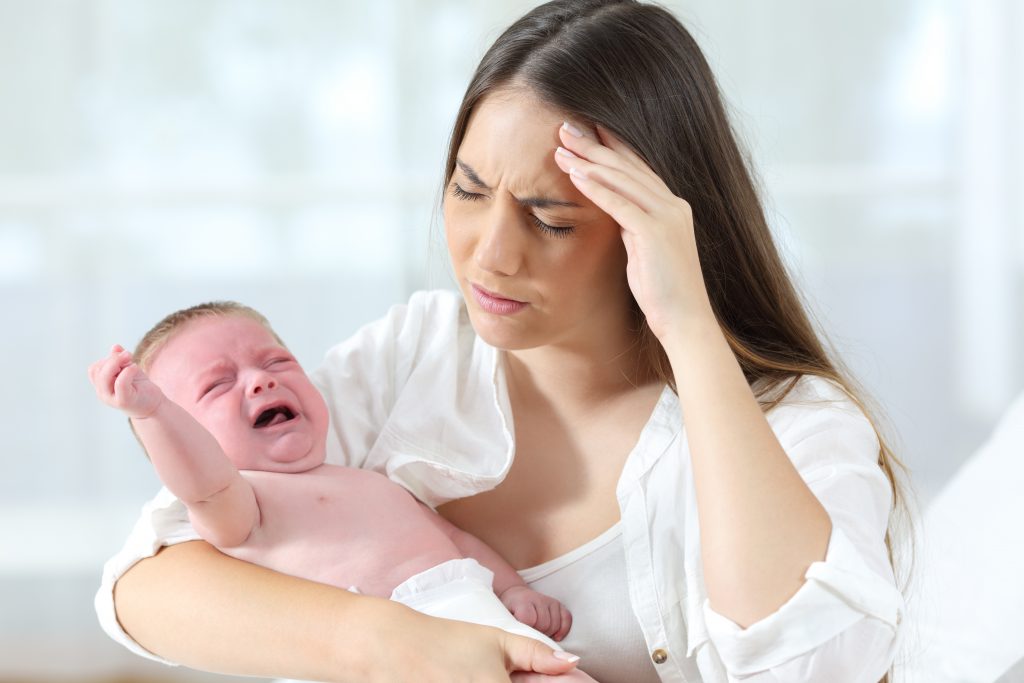 Desperate mother holding her angry baby crying