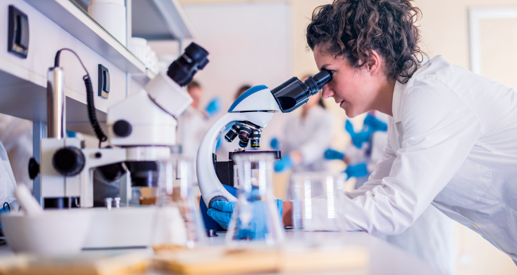 woman looking through microscope