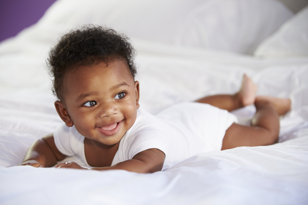 cute baby laying on tummy on bed