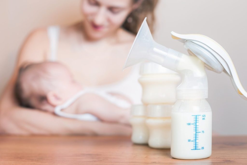 mom holding baby with breast pump