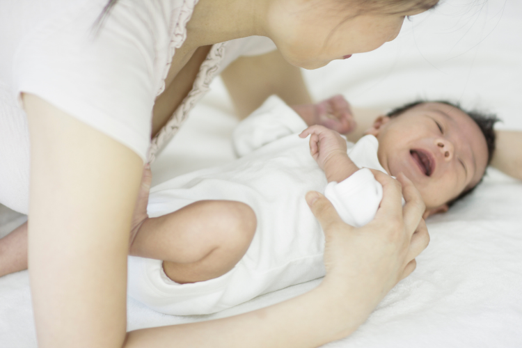 crying baby with mother over him